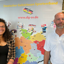 Zwei Personen stehen vor einem Schaubild des Deutschen Gehörlosen-Sportverbands